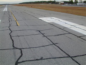 Overview photo of a runway showing block cracking over a large area of the runway surface.            The block cracking is noticable on the pavement as a pattern of rectangular pieces of pavement where the visible longitudinal and transverse cracks have defined the borders of the           pavement rectangles.  The majority of the cracks in the photo have been sealed.