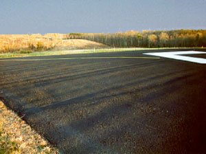 Overview photo of the end of a runway pavement.  Within the photo a series of deep transverse           corrugations are visible on the pavement.
