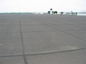 Overview photo of an apron pavement with a uniform rectangular pattern of low-severity           tranvserse and longitudinal cracks.  The pattern is the result of cracks that have reflected through the asphalt surface at the joints of the PCC slabs below.