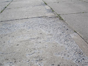 Overview photo showing showing high-severity scaling.  The PCC pavement surface in this photo           is severly scaled, and there is noticable loose material on the surface.